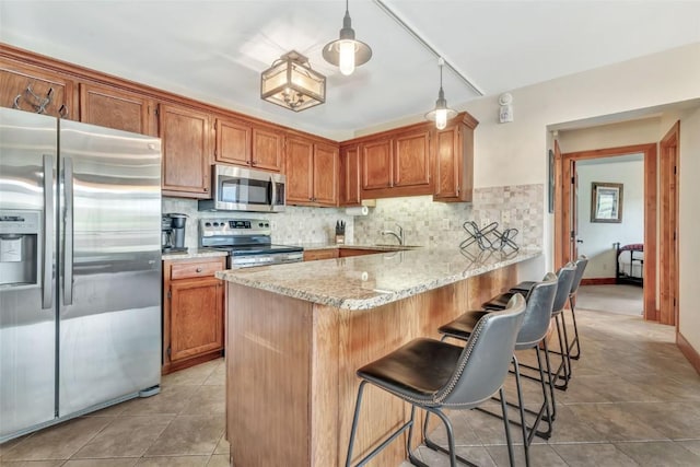 1995 Storm Meadows Dr Unit 307, Steamboat Springs, CO 80487 - kitchen featuring stainless steel appliances, tasteful backsplash, light tile patterned floors, and brown cabinets