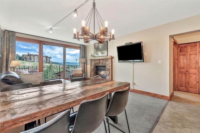 1995 Storm Meadows Dr Unit 307, Steamboat Springs, CO 80487 - dining space with a chandelier, light tile patterned flooring, track lighting, and a glass covered fireplace