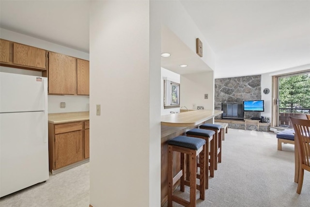 210 E Ln Bonte St Unit 121, Dillon, CO 80435 - kitchen with freestanding refrigerator, light carpet, a breakfast bar, open floor plan, and a stone fireplace