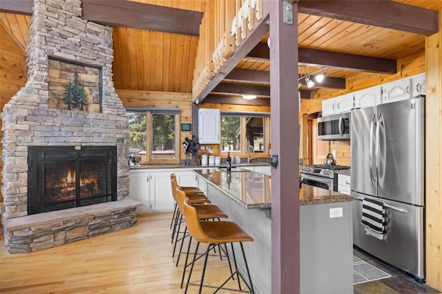 36 Silk Sisters Pl, Fairplay, CO 80440 - kitchen featuring stainless steel appliances, wooden ceiling with exposed beams, a fireplace, white cabinets, and stone counters