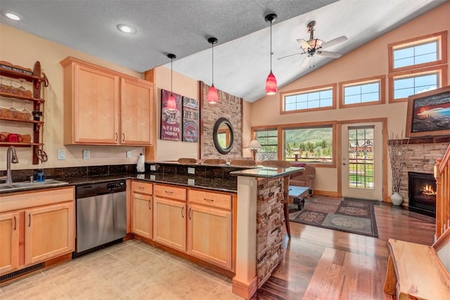kitchen with a peninsula, light brown cabinetry, a sink, open floor plan, and dishwasher