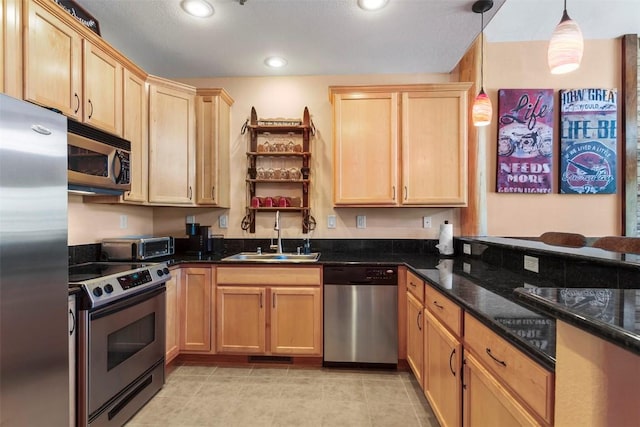 kitchen with pendant lighting, appliances with stainless steel finishes, light brown cabinets, and a sink