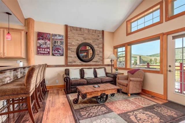 living area with high vaulted ceiling, baseboards, and wood finished floors