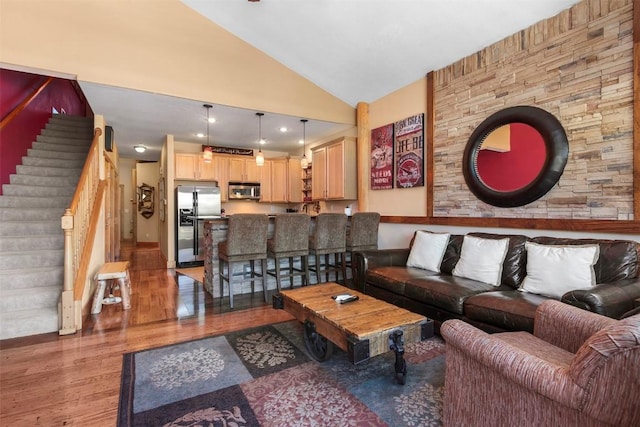 living room with stairway, vaulted ceiling, and wood finished floors