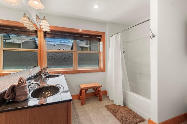 bathroom with shower / bath combination with curtain, baseboards, tile patterned flooring, and a sink