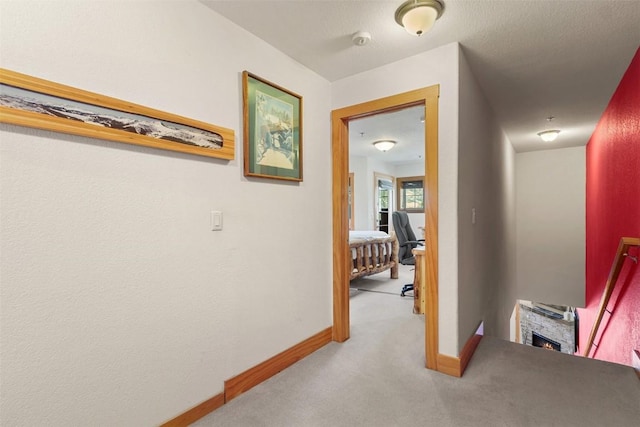 corridor with baseboards and carpet flooring