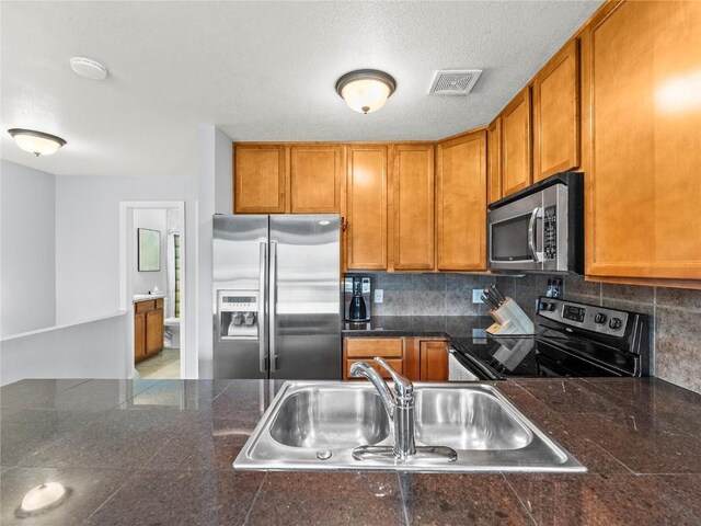 414 Tenderfoot St Unit 1, Dillon, CO 80435 - kitchen featuring stainless steel appliances, tile countertops, a sink, brown cabinetry, and backsplash