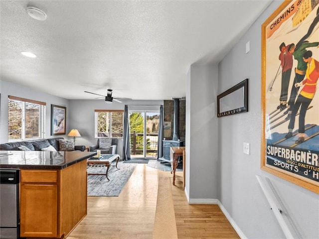 414 Tenderfoot St Unit 1, Dillon, CO 80435 - living room featuring light wood-style flooring, ceiling fan, a textured ceiling, baseboards, and a wood stove