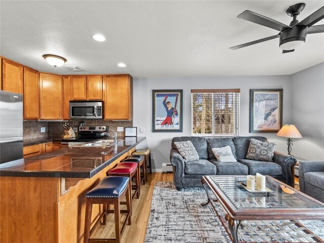 414 Tenderfoot St Unit 1, Dillon, CO 80435 - kitchen featuring stainless steel appliances, brown cabinetry, light wood-style flooring, open floor plan, and recessed lighting