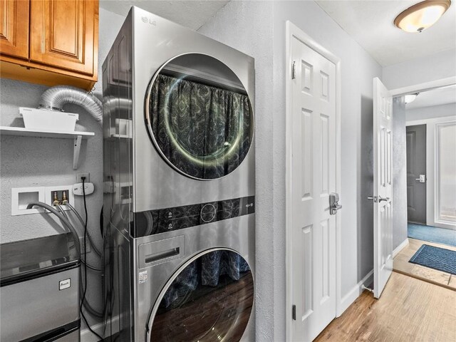 414 Tenderfoot St Unit 1, Dillon, CO 80435 - washroom featuring stacked washer and clothes dryer, cabinet space, wood finished floors, and baseboards