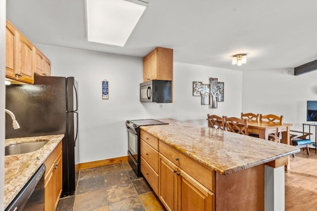 kitchen with a peninsula, a sink, baseboards, light stone counters, and black appliances