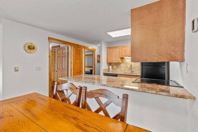 kitchen with a kitchen breakfast bar, a sink, black electric cooktop, backsplash, and a peninsula