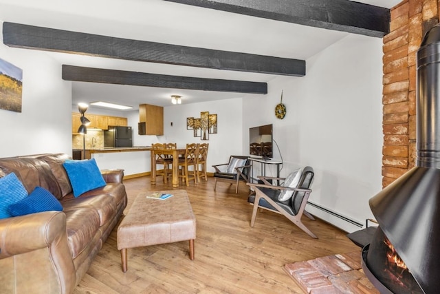 living room with a baseboard heating unit, beam ceiling, light wood-style floors, and a wood stove
