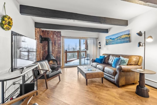 living area with a baseboard heating unit, light wood-style flooring, beam ceiling, and a wood stove
