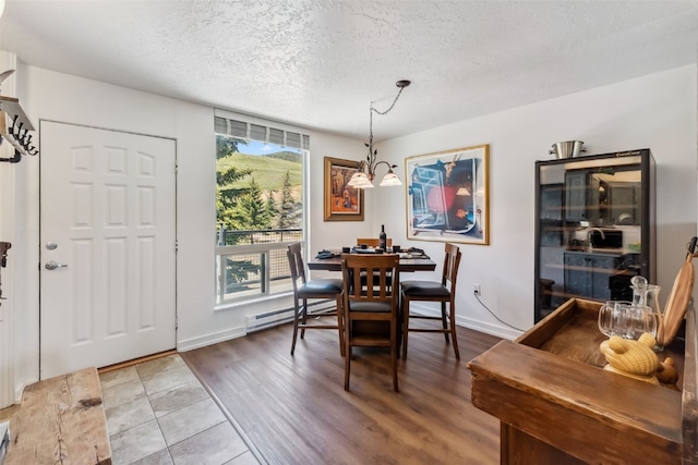 340 Straight Creek Dr Unit 206, Dillon, CO 80435 - dining space featuring baseboard heating, a textured ceiling, and wood finished floors