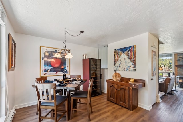 340 Straight Creek Dr Unit 206, Dillon, CO 80435 - dining space featuring a textured ceiling, wood finished floors, a chandelier, and a baseboard heating unit