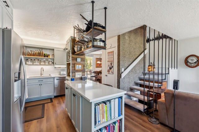 340 Straight Creek Dr Unit 206, Dillon, CO 80435 - kitchen featuring stainless steel appliances, a textured ceiling, open shelves, wood finished floors, and light countertops