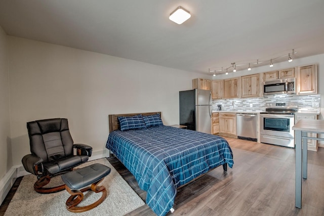 bedroom with hardwood / wood-style flooring and stainless steel fridge