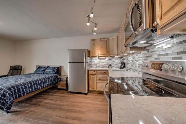 kitchen with light brown cabinets, sink, light hardwood / wood-style flooring, decorative backsplash, and stainless steel appliances