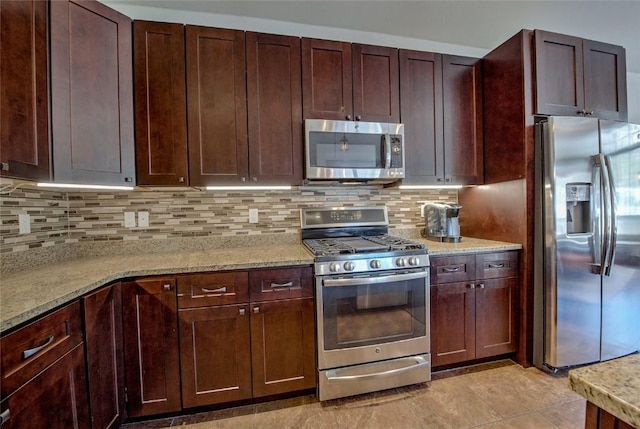 kitchen with decorative backsplash, light tile patterned floors, light stone countertops, and appliances with stainless steel finishes