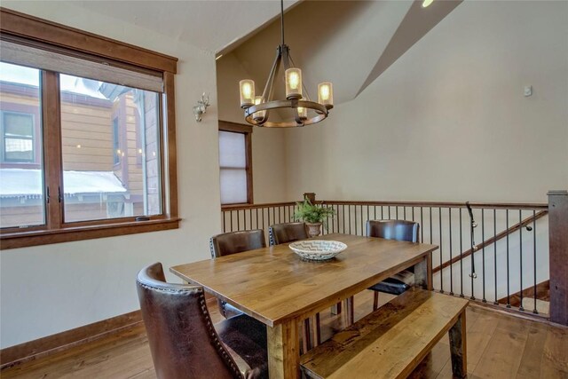 dining area featuring a chandelier, light hardwood / wood-style floors, and vaulted ceiling