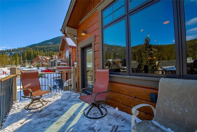 snow covered patio featuring a mountain view and a balcony