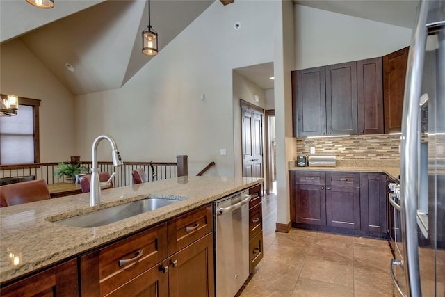 kitchen featuring light stone counters, stainless steel appliances, vaulted ceiling, sink, and pendant lighting