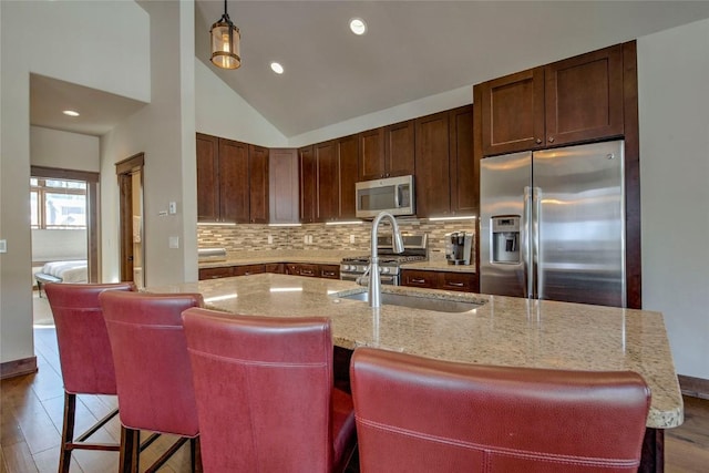 kitchen featuring a kitchen island with sink, a breakfast bar, decorative light fixtures, and appliances with stainless steel finishes