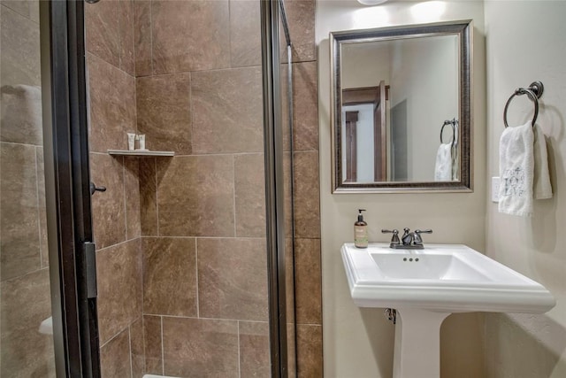 bathroom with a shower with door and sink