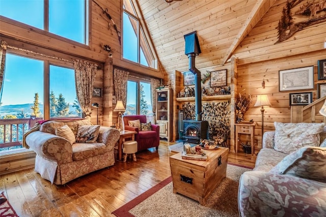living room with high vaulted ceiling, a wood stove, hardwood / wood-style floors, wooden walls, and wooden ceiling