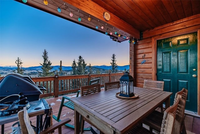 deck at dusk with outdoor dining area and a mountain view