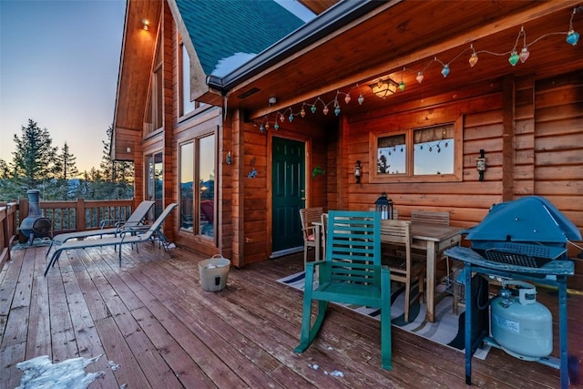 deck at dusk with outdoor dining area and a grill