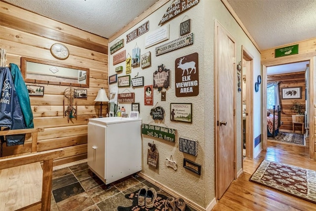 laundry room featuring a textured ceiling, wooden walls, and baseboards