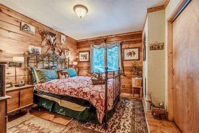 bedroom with wood finished floors, wood walls, and a textured ceiling
