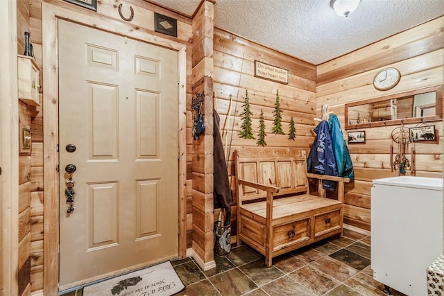 mudroom featuring a textured ceiling and wood walls