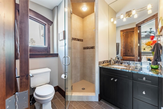 bathroom featuring toilet, a stall shower, vanity, a wealth of natural light, and baseboards