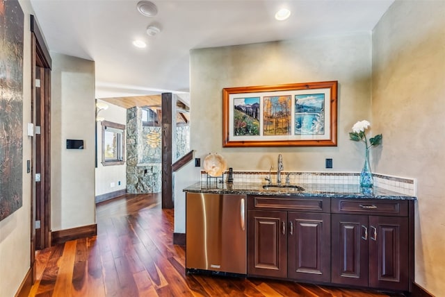 bar featuring a sink, tasteful backsplash, baseboards, dark wood-type flooring, and refrigerator