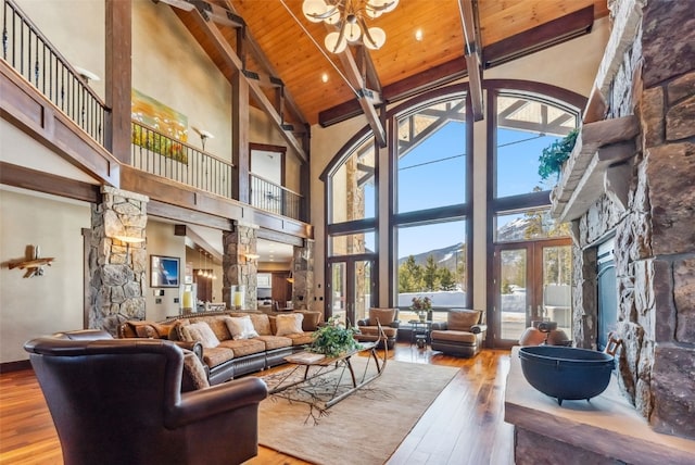 living area featuring high vaulted ceiling, hardwood / wood-style flooring, an inviting chandelier, a fireplace, and wooden ceiling