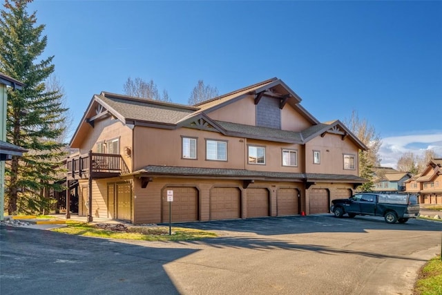 view of front of home featuring an attached garage, aphalt driveway, and stairway