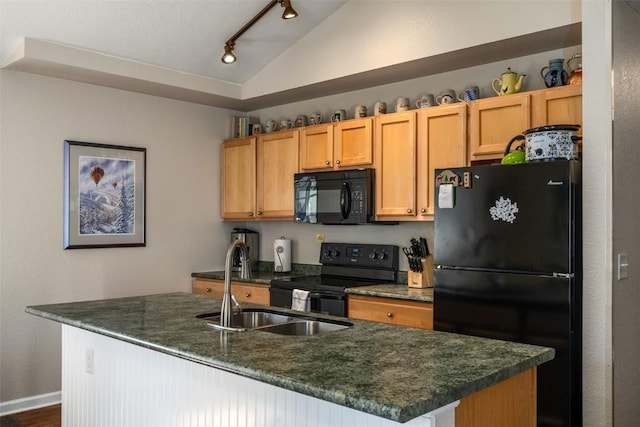 kitchen featuring lofted ceiling, an island with sink, rail lighting, a sink, and black appliances