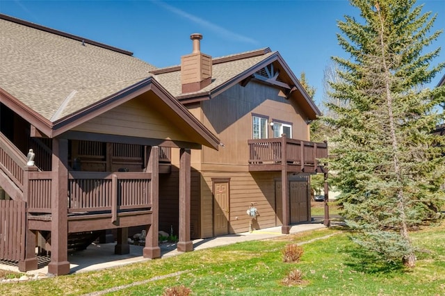 3303 Covey Cir Unit 804, Steamboat Springs, CO 80487 - back of house featuring a yard, roof with shingles, a chimney, and a deck