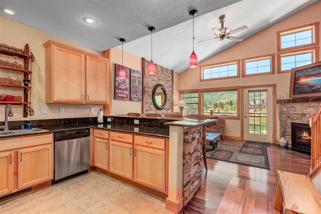 kitchen with light brown cabinets, a peninsula, a sink, stainless steel dishwasher, and open floor plan