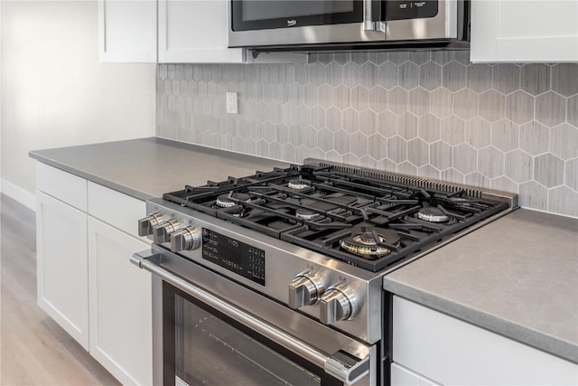 kitchen with white cabinets, decorative backsplash, and stainless steel gas range oven