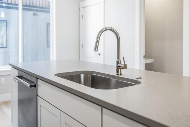 kitchen featuring white cabinets, light countertops, a sink, and stainless steel dishwasher