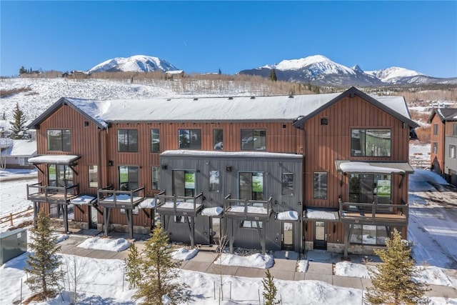 snow covered back of property featuring a mountain view