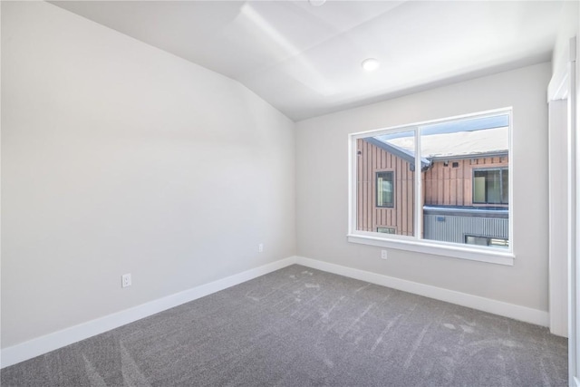 carpeted spare room with vaulted ceiling and baseboards
