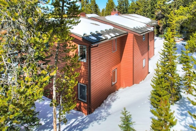 snow covered property featuring a shingled roof