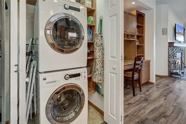 laundry room with stacked washer / drying machine, light wood-style flooring, baseboards, and laundry area