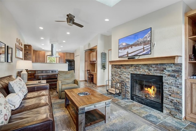 living area featuring recessed lighting, a ceiling fan, and a stone fireplace