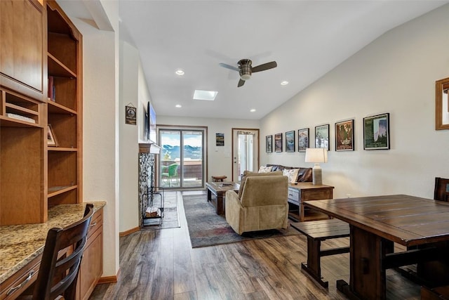 living area featuring dark wood-style floors, baseboards, recessed lighting, vaulted ceiling with skylight, and ceiling fan